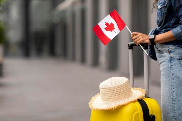 Canada Permanent Resident Visas Canada Visa and Immigration Images and Photos: 3. A photo of unidentified woman with a yellow luggage travelling to Canada with permanent resident visa. Photo credit: Freepik. https://www.freepik.com/premium-photo/cropped-woman-traveller-holding-flag-canada-going-abroad_34246342.htm#