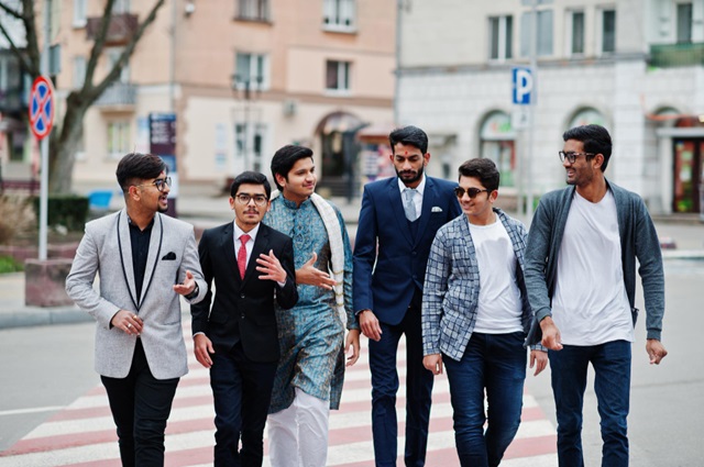 45,000 UK Seasonal Workers Visa Sponsorship Companies and Agencies (Sponsors) 2024/2025 to 2029 for Nigerians and Other Asian Countries including Nepalese, Indonesians, Indians, Pakistanis, and Bangladeshi. Images: 3: A group of six young South Asian men, dressed in a mix of formal and traditional clothing, walk together on a city crosswalk, symbolizing the arrival of successful applicants for the UK Seasonal Worker Visa.